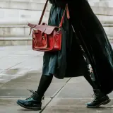 Czarne martensy i czerwona torba tworzą stylowy zestaw. Długa, czarna sukienka dodaje elegancji.