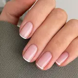 Dłoń z idealnie wykonanymi, eleganckimi paznokciami french. Delikatny róż i klasyczna biel tworzą ponadczasowy manicure.