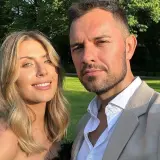 Aleksandra Gryś z mężem na tle ogrodu. Uśmiechnięta para pozuje do zdjęcia w słoneczny dzień.