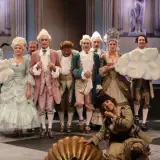 Piękna Lucynda w teatrze na 6. piętrze, w otoczeniu aktorów w strojach z epoki, przygotowuje się do spektaklu.