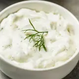 Salsa yogurt ricetta cremosa con aneto fresco e una fetta di limone sullo sfondo.