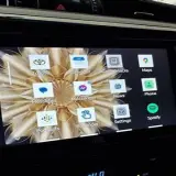 Ekran samochodu z aplikacją Android Auto. Widoczne ikony: Toyota, Kalendarz, Gry, Mapy, Wiadomości, Telefon, Spotify, Ustawienia, Podcasty, Przypomnienia, Messenger.