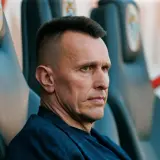 Skupiony trener Zagłębia Lubin siedzi na ławce rezerwowych, analizując grę.