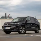 Czarny VW Tiguan Allspace na parkingu pod chmurką. Elegancki SUV z chromowanymi detalami i nowoczesnymi felgami.
