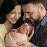Ciepłe sesje noworodkowe z rodzicami. Mama i tata z czułością tulą swoje maleństwo, tworząc niezapomniane wspomnienia.