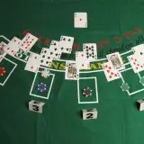 Kier karty na zielonym stole do blackjacka. Widoczne karty, żetony i kostki z numerami.