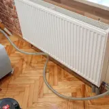 Profesjonalne płukanie instalacji grzewczej w Warszawie. Sprzęt do czyszczenia podłączony do grzejnika.