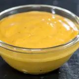 Gęsty, żółty sos curry na mleczku kokosowym w szklanej miseczce. Dlaczego sos się warzy i jak to naprawić?