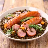Saucisse lentille Cookeo : un plat réconfortant avec des saucisses savoureuses sur un lit de lentilles, carottes et romarin.