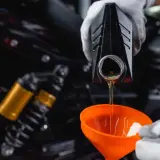 Olej 10w40 do jakich silników? Wlewanie oleju do motocykla przez pomarańczowy lejek.