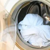 Białe ręczniki w bębnie pralki. Dowiedz się, jak prać ręczniki, żeby nie śmierdziały i były świeże.