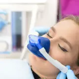 Pacjentka w trakcie zabiegu stomatologicznego z maską do sedacji. To metoda, która pozwala na komfortowe przejście przez leczenie.
