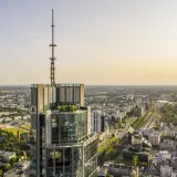 Widok z lotu ptaka na wieżowiec w Warszawie z anteną na szczycie. Zastanawiasz się, ile pięter ma Warsaw Tower? To imponująca budowla.