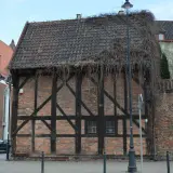 Stare kamienice w Gdańsku, z charakterystyczną cegłą i drewnianą konstrukcją, porośnięte bluszczem.