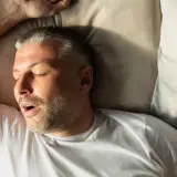 Mann schläft mit offenem Mund, was auf leichte Schlafapnoe hindeuten könnte.