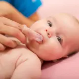 Delikatne czyszczenie buzi niemowlaka. Gdy pojawią się pierwsze ząbki, warto pomyśleć o profilaktyce, a nawet o leczeniu pleśniawek.