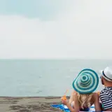 Para relaksu na plaży w Mielnie. Para w kapeluszach popija drinki, ciesząc się widokiem morza. Idealne mielno atrakcje dla dorosłych.