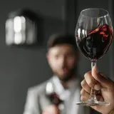 Verre de vin rouge, parfait pour accompagner un foie gras. Des mains lèvent des verres pour un toast.