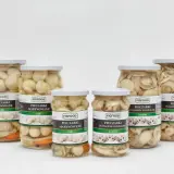 Sześć słoików z marynowanymi pieczarkami Figfood, w tym całe i krojone, na białym tle.