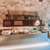 Wnętrze jednej z nowych restauracji w Warszawie. Widać piec do pizzy, bar i gości.