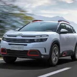 Biały Citroen C5 Aircross z czerwonymi akcentami pędzi po drodze. Wiele osób szuka o nim **citroen c5 aircross opinie**.