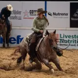 Une cavalière effectue un virage serré, soulevant de la poussière avec son cheval lors d'une compétition de cutting cheval.