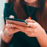 Kobieta pisze na telefonie, planując zakupy na Vinted z opcją PayPo.