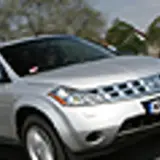 Srebrny Nissan Murano 3.5 V6 na drodze, z drzewami i innymi samochodami w tle.