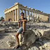 Hombre sentado en la Acrópolis, disfrutando de la vista del Partenón. ¡Una parada obligatoria si buscas qué ver en Atenas en 2 días!