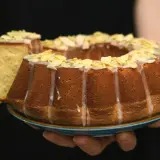 Pyszna babka na oleju siostry Anastazji, udekorowana lukrem i płatkami migdałów, z odciętym kawałkiem.