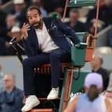 Sędziowie tenisa ziemnego WTA w akcji. Sędzia na krześle z mikrofonem, gestykuluje do gracza.
