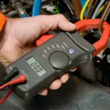 Elektryk mierzy spadek napięcia na przewodzie za pomocą cęgów mierniczych.