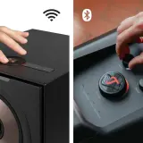 Dwie ręce sterują głośnikami. Jedna dotyka panelu z ikoną Wi-Fi, druga pokrętłami basu i sopranów. To pokazuje, jak łatwo jest używać funkcji airplay.