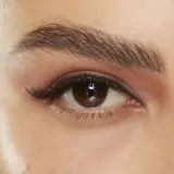 Närbild på ett brunt öga med perfekt trådade ögonbryn, dramatisk eyeliner och voluminösa fransar.