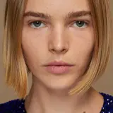 Primer plano de una mujer con un corte bob rubio y un vestido azul brillante.