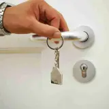 Main tenant ouvre la porte avec une clé en forme de maison. Les travaux ne sont pas finis, mais le paiement est attendu.