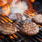 Soczyste burgery z grilla skwierczą na rozżarzonych węglach, otoczone dymem i płomieniami. Idealne na letnie popołudnie.