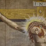 Zbliżenie na cierpiącego Jezusa na krzyżu. Widoczna korona cierniowa, rana na dłoni i napis INRI.