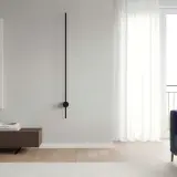 Un minimalista aplique pared lineal negro ilumina un salón moderno con sofá azul y cuadro abstracto.