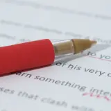 Czerwony długopis na białej kartce z tekstem. Podkreślone fragmenty tekstu sugerują korektę, być może dotyczącą tego, jakie są najczęstsze błędy w tworzeniu sztucznych języków (conlangs).