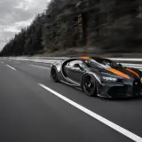 Czarny Bugatti Chiron Super Sport z pomarańczowymi pasami pędzi po pustej autostradzie.