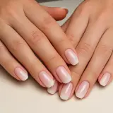 Manos con manicura rusa impecable, luciendo un degradado suave de rosa a blanco.