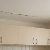 Pęknięcie na suficie nad szafkami kuchennymi. Może to być sygnał problemów z konstrukcją, wymagający uwagi i być może rekojmia.