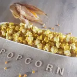 Leckeres Popcorn in einer Schale, daneben ein Maiskolben. Informiere dich über die Mais Nährwerte für einen gesunden Snack.