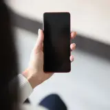 Dłoń trzyma telefon z czarnym ekranem. Czekam na powiadomienie.