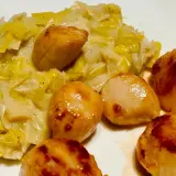 Saint-Jacques poêlées sur un lit de fondue de poireaux crémeuse, un plat savoureux et réconfortant.