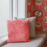 Färgglad tapetsera non woven med djurmotiv i ovala ramar. Två kuddar, en korallfärgad och en grå, vilar på en fönsterbänk.