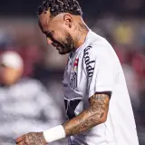 Neymar w białej koszulce Santos, z tatuażami na ramieniu, wygląda na zamyślonego. To właśnie tam gra Neymar.
