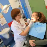 Dentystka bada zęby młodej pacjentki w gabinecie stomatologicznym.