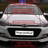 Biały samochód z zaznaczonymi światłami: kierunkowskazy, awaryjne, mijania, drogowe, pozycyjne i do jazdy dziennej. Przydatne do nauki przed egzaminem na prawo jazdy.
